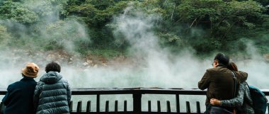 Beitou Parkı 'ndaki ünlü Beitou Termal Vadisi' nde, Tayvan 'ın Taipei şehrindeki ağaçların arasından süzülen sıcak kaynak kaynayan buharı ile turist seyahati.