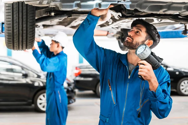 Mekanikern Och Hans Assistent Undersöker Bilens Botten Med Blinkande Ljus — Stockfoto