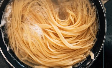 Çelik tavada kaynar su içinde spagetti makarnası yakın plan. Al Dente Spagettisi hazırlığı.