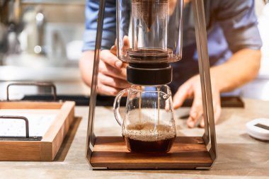 Erkek barista, damlatma adı verilen alternatif bir yöntemle kahve yapıyor. Modern kahve öğütücüsünü, kahve büfesini kapat ve beton tezgahın üstüne dök..