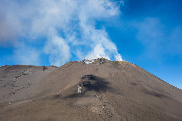 Снимок летающего беспилотника с вулканического кратера на горе Этна, один из кратеров с фланга, представляет собой круглую впадину в земле, вызванную вулканической активностью, и, как правило, имеет форму чаши, на которой также изображены люди, идущие
