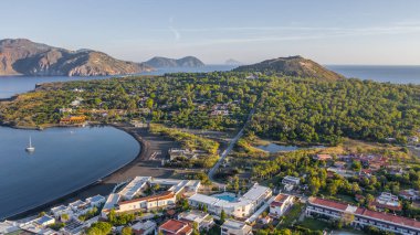 İtalya 'nın Vulcano şehrinde, Porto di Ponente' de küçük bir limanda yatları olan siyah kumlu kumsalın uçan insansız hava aracının havadan çekilmiş fotoğrafı.)