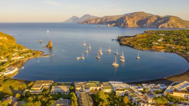 İtalya 'nın Vulcano şehrinde, Porto di Ponente' de küçük bir limanda yatları olan siyah kumlu kumsalın uçan insansız hava aracının havadan çekilmiş fotoğrafı.)