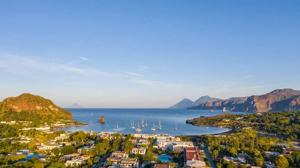 İtalya 'nın Vulcano şehrinde, Porto di Ponente' de küçük bir limanda yatları olan siyah kumlu kumsalın uçan insansız hava aracının havadan çekilmiş fotoğrafı.)