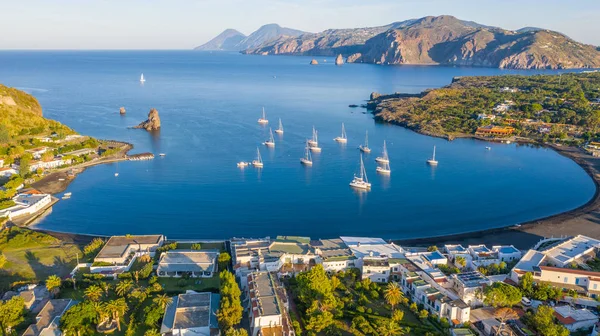 İtalya 'nın Vulcano şehrinde, Porto di Ponente' de küçük bir limanda yatları olan siyah kumlu kumsalın uçan insansız hava aracının havadan çekilmiş fotoğrafı.)