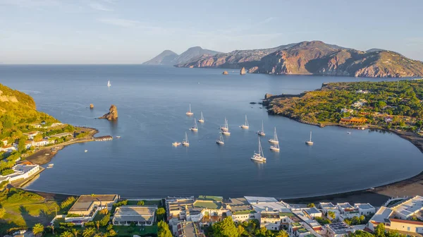 İtalya 'nın Vulcano şehrinde, Porto di Ponente' de küçük bir limanda yatları olan siyah kumlu kumsalın uçan insansız hava aracının havadan çekilmiş fotoğrafı.)