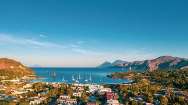 İtalya 'nın Vulcano şehrinde, Porto di Ponente' de küçük bir limanda yatları olan siyah kumlu kumsalın uçan insansız hava aracının havadan çekilmiş fotoğrafı.)