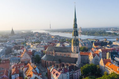 Daugava Nehri 'nin arka planında ve şehir merkezinde bulunan St. Peter Kilisesi' ne uçan insansız hava aracı panoramik görüntüsü (dizi).)