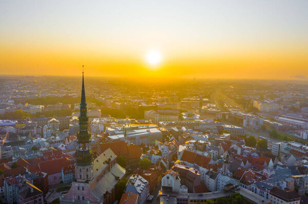 Aerial view photo from flying drone panoramic to St. Peter's Church and the Old Town on the background of the Daugava River and downtown on a beautiful early morning sunrise (series)