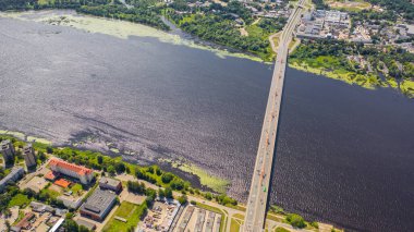 Daugava nehri ve Letonya 'nın Riga kentindeki Riga şehrinin arka planında bulunan Güney Köprüsü' nün (Dienvidu eğikliği) insansız hava aracı panoramik görüntüsü. (seri)