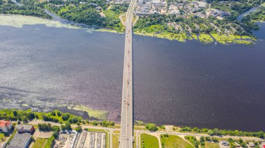 Daugava nehri ve Letonya 'nın Riga kentindeki Riga şehrinin arka planında bulunan Güney Köprüsü' nün (Dienvidu eğikliği) insansız hava aracı panoramik görüntüsü. (seri)