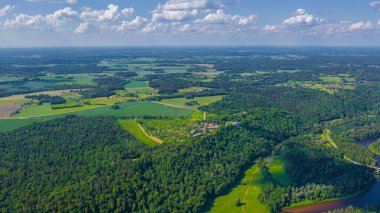Sigulda 'nın güzel ormanları, çayırlar ve akan Gauja nehri üzerinde uçan dron' dan panoramik hava manzaralı fotoğraf. Sigulda, Letonya yazın)