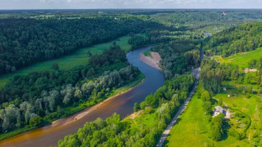 Sigulda 'nın güzel ormanları, çayırlar ve akan Gauja nehri üzerinde uçan dron' dan panoramik hava manzaralı fotoğraf. Sigulda, Letonya yazın)