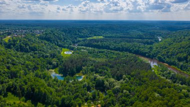 Sigulda 'nın güzel ormanları, çayırlar ve akan Gauja nehri üzerinde uçan dron' dan panoramik hava manzaralı fotoğraf. Sigulda, Letonya yazın)