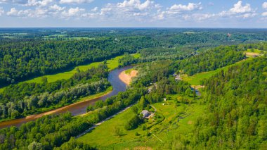 Sigulda 'nın güzel ormanları, çayırlar ve akan Gauja nehri üzerinde uçan dron' dan panoramik hava manzaralı fotoğraf. Sigulda, Letonya yazın)