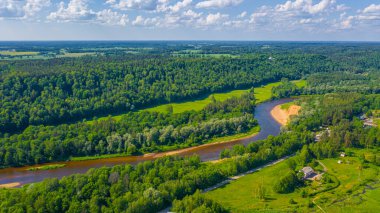 Sigulda 'nın güzel ormanları, çayırlar ve akan Gauja nehri üzerinde uçan dron' dan panoramik hava manzaralı fotoğraf. Sigulda, Letonya yazın)
