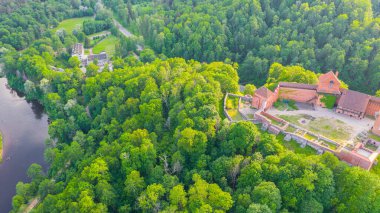 Güneşli bir yaz günü Sigulda, Letonya 'da, Turaida Kalesi' nin ortasında, Gauja Nehri üzerinde uçan dronun panoramik hava görüntüsü. (seri)