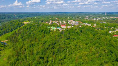 Güneşli bir yaz gününde Sigulda üzerinde uçan dron 'dan gelen güzel panoramik hava manzaralı fotoğraf ormanların ve kırsal alanların arka planına karşı. Sigulda, Letonya (dizi)
