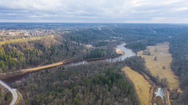 Güneşli bir kış gününde Sigulda üzerinde uçan İHA 'dan gelen güzel panoramik hava manzaralı fotoğraf ormanların ve kırsal alanların arka planında karsız. Sigulda, Letonya (dizi)