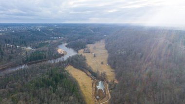 Güneşli bir kış gününde Sigulda üzerinde uçan İHA 'dan gelen güzel panoramik hava manzaralı fotoğraf ormanların ve kırsal alanların arka planında karsız. Sigulda, Letonya (dizi)