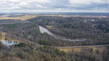 Güneşli bir kış gününde Sigulda üzerinde uçan İHA 'dan gelen güzel panoramik hava manzaralı fotoğraf ormanların ve kırsal alanların arka planında karsız. Sigulda, Letonya (dizi)