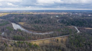 Güneşli bir kış gününde Sigulda üzerinde uçan İHA 'dan gelen güzel panoramik hava manzaralı fotoğraf ormanların ve kırsal alanların arka planında karsız. Sigulda, Letonya (dizi)