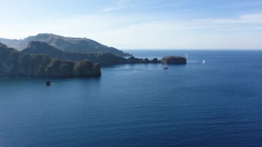 Porto di Ponente, Vulcano, Lipari ve Salina Aeolian Adaları Tyrhenian Denizi, Sicilya, İtalya 'da yatları olan siyah kumlu plajın güzel panoramik 4K videosu.
