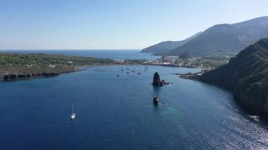 Porto di Ponente, Vulcano, Lipari ve Salina Aeolian Adaları Tyrhenian Denizi, Sicilya, İtalya 'da yatları olan siyah kumlu plajın güzel panoramik 4K videosu.