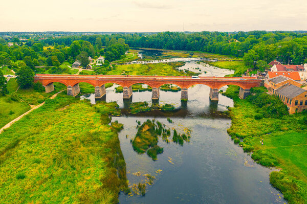 Beautiful panoramic aerial view photo from flying drone to Venta Rapid waterfall,the widest waterfall in Europe and the third longest brick bridge in Europe on a summer day in Kuldiga, Latvia.(series)