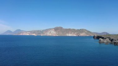 Vulcano adasındaki kayalarda uçan dron ve parlak mavi Tyrhenian Denizi Aeolian Adaları, Sicilya, İtalya 'daki (dizi) 4K panoramik video)