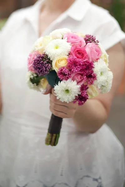 新娘手里拿着一束花 背景是新娘的白色连衣裙 花束中的花 一个年轻的女人左手拿着结婚花束 — 图库照片