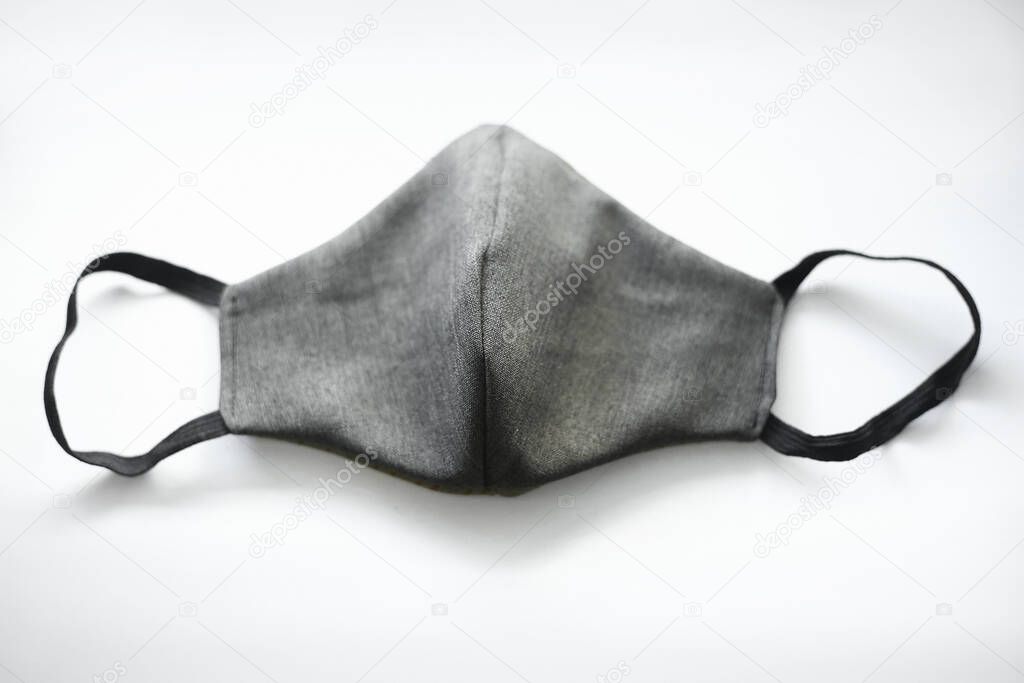fabric grey mask with black elastic bands on a white background. top view.