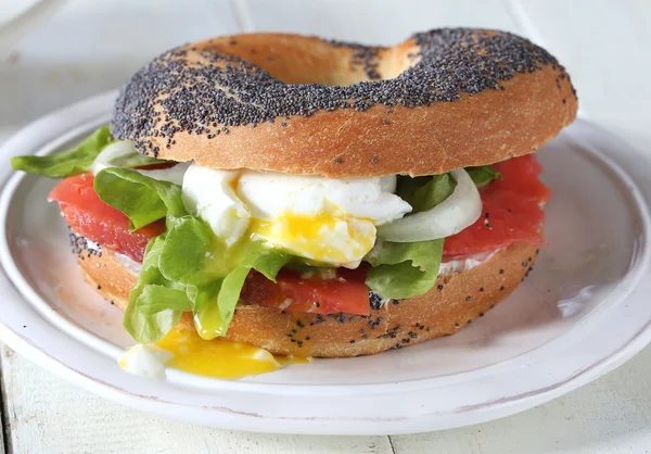 Bagel with salmon, egg and cream cheese on white plate — Stock Photo, Image