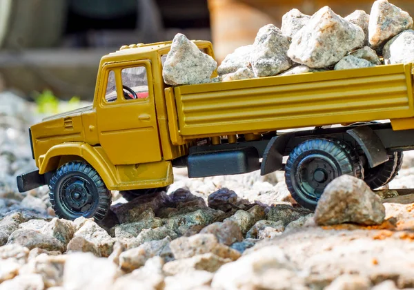 Toy model of a ZIL truck with a scale of 1:43 loaded with stones on a blurred background, sunny day, side view