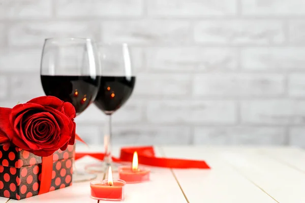 Una copa de vino, rosa, regalo y velas encendidas —  Fotos de Stock