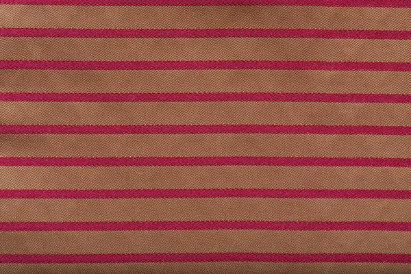 Colored striped coarse linen fabric closeup as background. Red-golden fabric striped texture pattern.