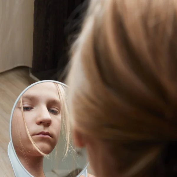 Teen girl unhappy with their appearance in mirror. Teenager girl examine pimples in mirror