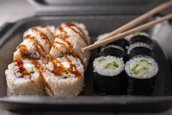 sushi or bento box with assorted sushi rolls pieces. Fish food selective focus.