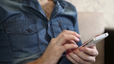 adam kanepede otururken bir akıllı telefon kullanır