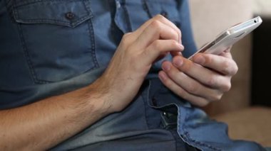 adam kanepede otururken bir akıllı telefon kullanır