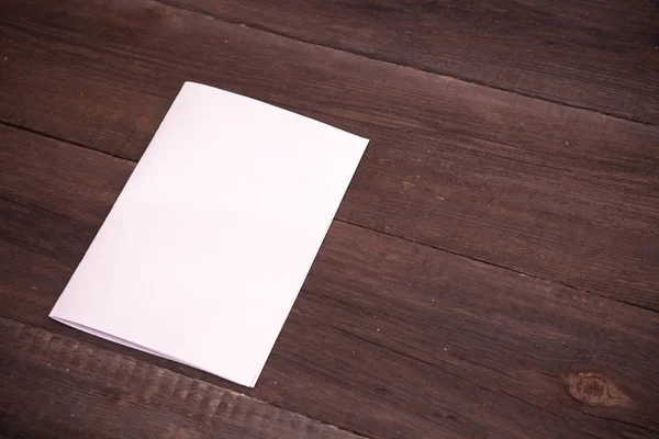 Sheet of paper folded in half on a wooden background — Stock Photo, Image