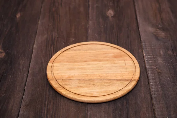 Tabla de cortar redonda de madera sobre un fondo de madera —  Fotos de Stock