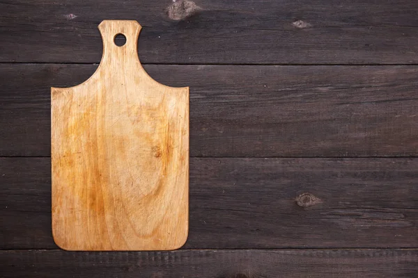 Wooden cutting board on a wooden background — Stock Photo, Image