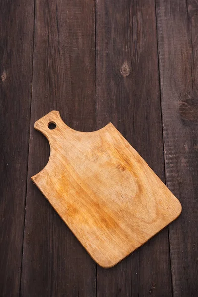 Wooden cutting board on a wooden background — Stock Photo, Image