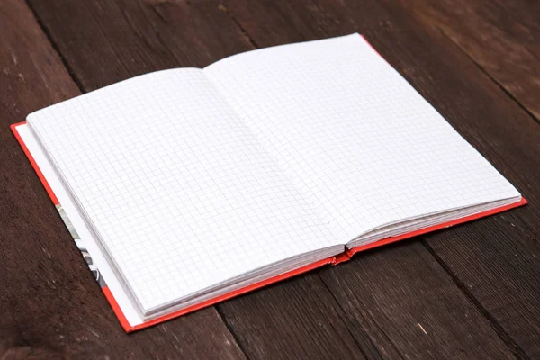 Open notebook in a cage on a wooden background — Stock Photo, Image