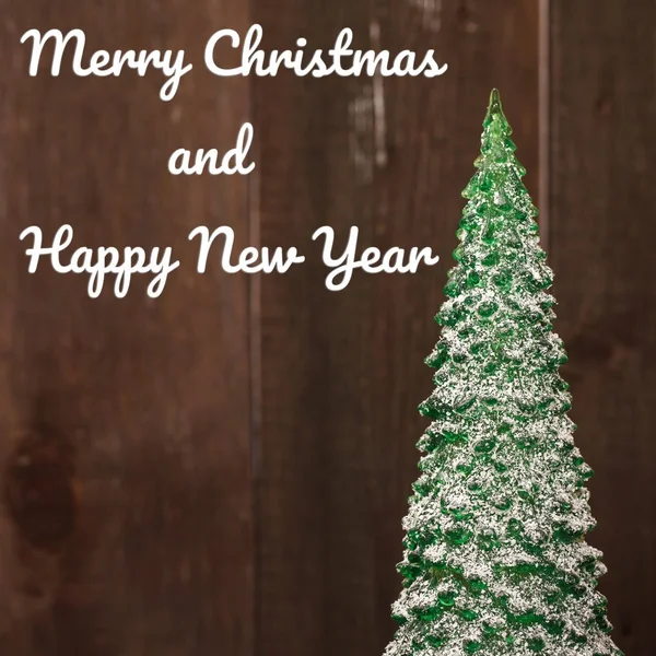 Malý vánoční stromeček suvenýr na dřevěné pozadí. s pozdravem c — Stock fotografie