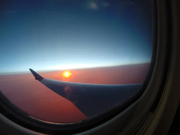 Ala de un avión en la puesta del sol roja — Foto de Stock