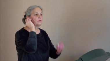  Woman put on wireless headphones walks on a treadmill and listening to music, aerobic exercise and endurance training at home.
