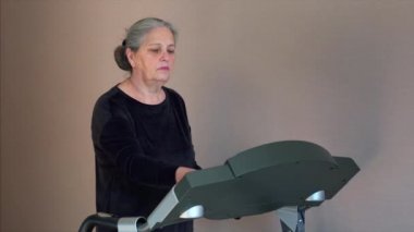Senior white hair woman is change mode of Treadmill before training at home.