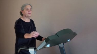 Woman Wearing Wireless Headphones, Listens Music while Running on a Treadmill. 